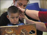 a boy reading with his mother while getting his hearing tested