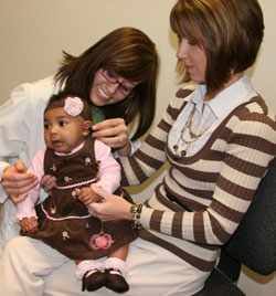 a baby, mother, and audiologist, hearing screening test in progress